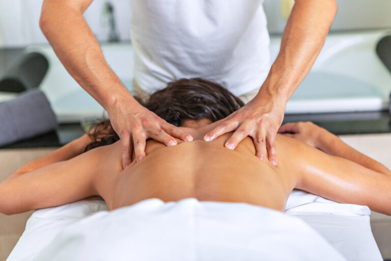 Rear view of relaxing woman lying face down on massage table receiving a back massage