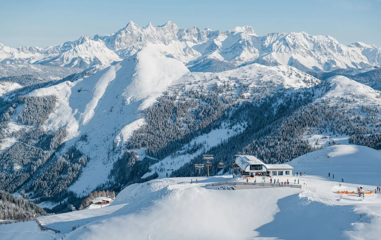 Schneebedeckte Berglandschaft mit einem Skilift und einer Bergstation im Vordergrund. Familienhotel Zauchenseehof