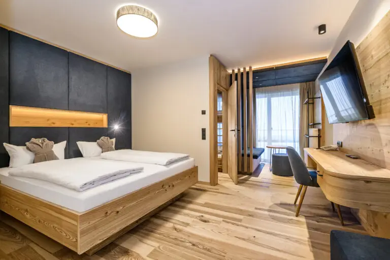 Hotelzimmer im Familienhotel Salzburger Land Zauchenseehof mit einem Doppelbett, Holzverkleidung und moderner Ausstattung.