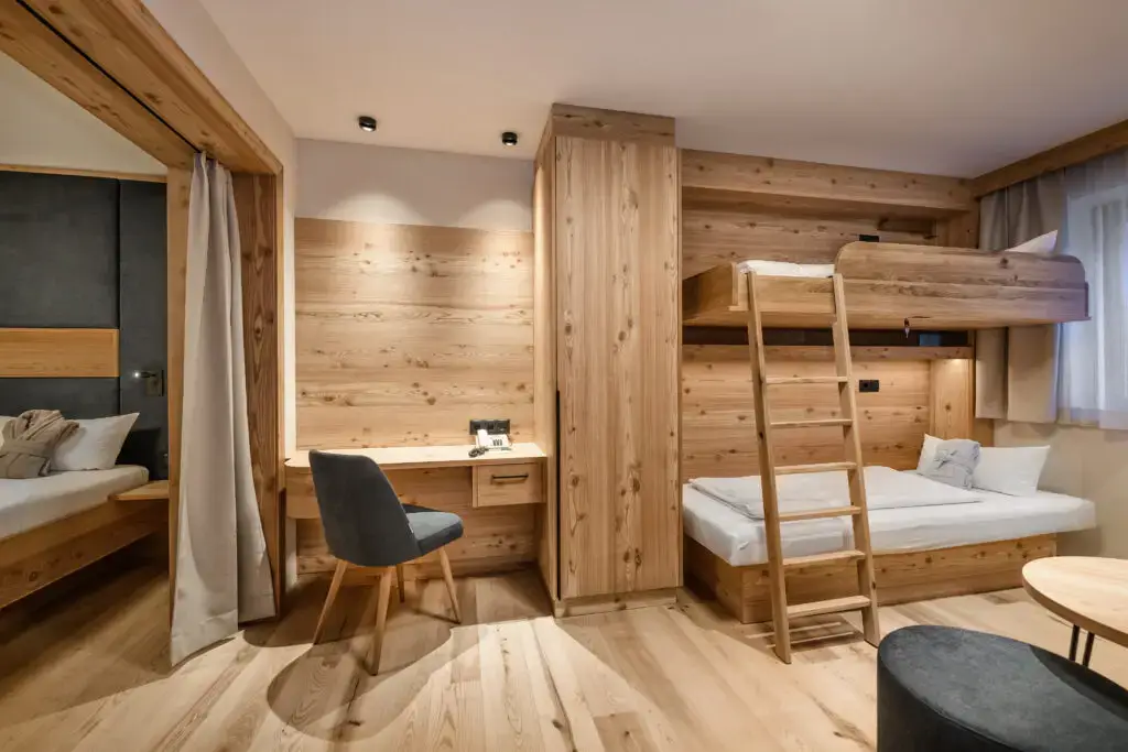 Family room with wooden interior, bunk bed and desk in the Zauchenseehof. Zauchenseehof Family Hotel