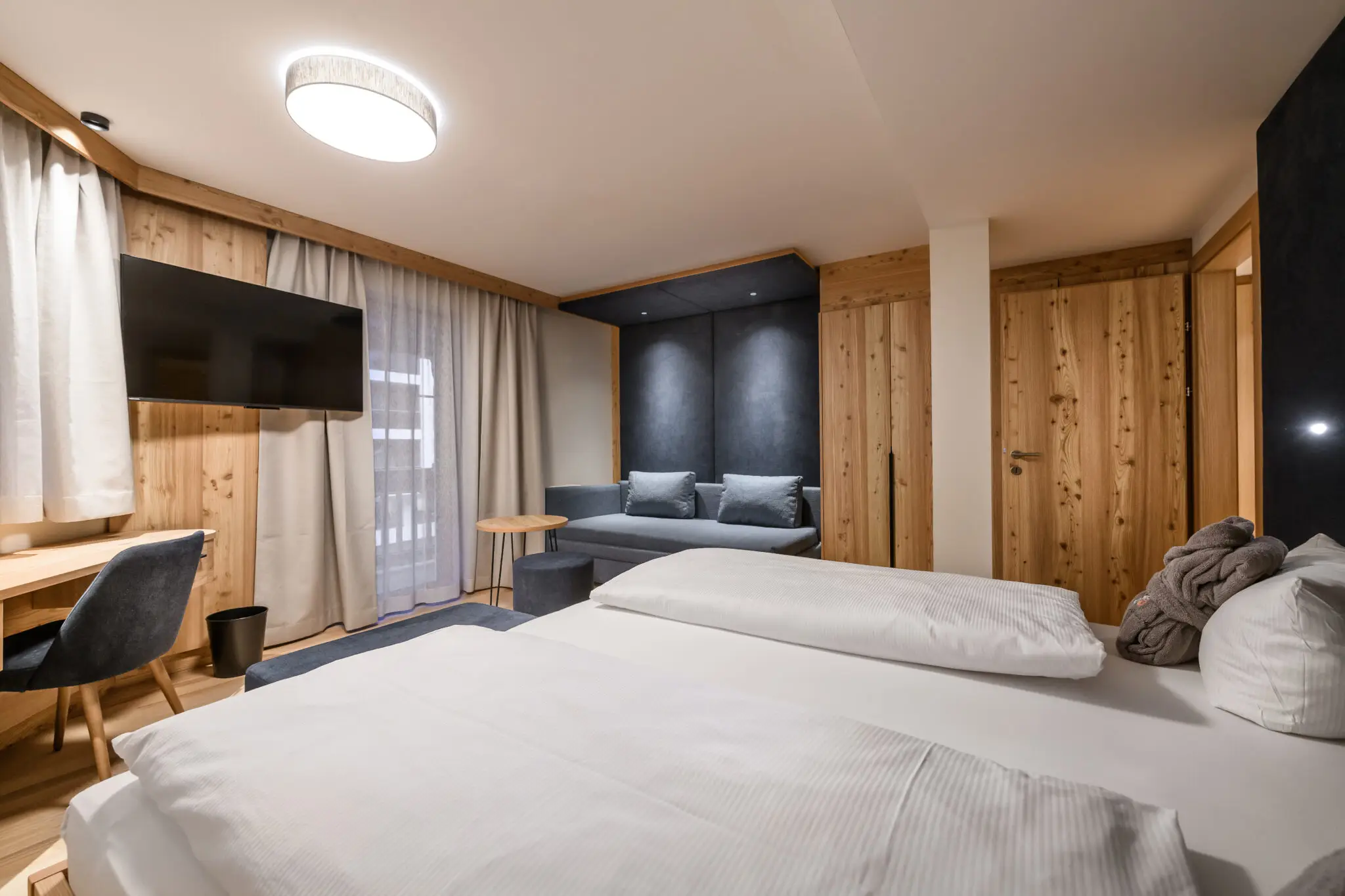 Modernes Hotelzimmer im Familienhotel Zauchenseehof Salzburger Land mit Doppelbett, Couch und Fernseher.