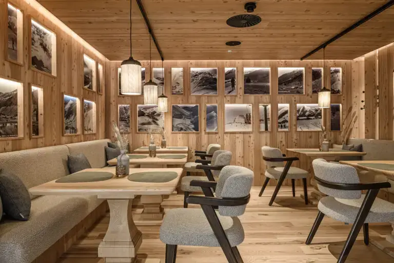 Ein gemütliches Restaurant im Familienhotel Zauchenseehof Salzburger Land mit Holzwänden, Tischen und Bildern von Bergen an der Wand.