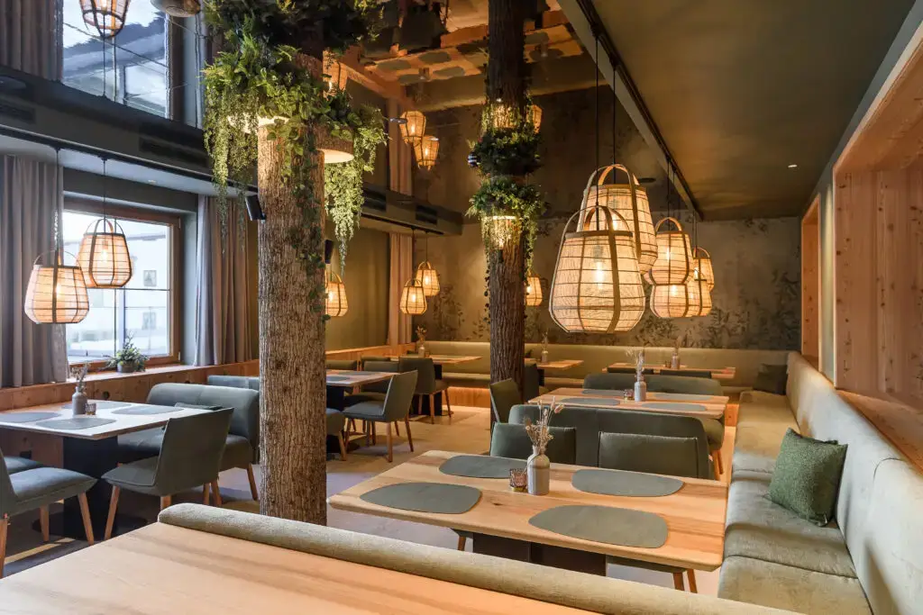 Interior view of a restaurant with wood decor, large lamps, and cozy seating areas at the Zauchenseehof family hotel Salzburger Land