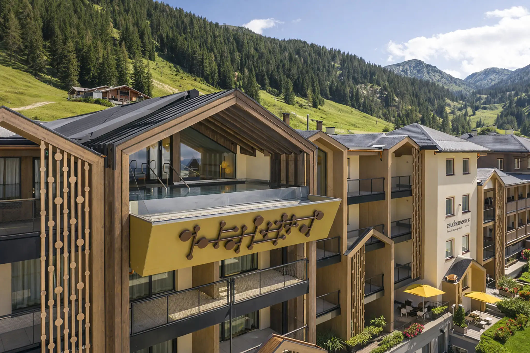 Ansicht des Familienhotel Zauchenseehof mit Holzfassade und Balkonen, umgeben von Bergen und Bäumen im Salzburger Land. Familienurlaub Wellnessurlaub Skiurlaub in Österreich